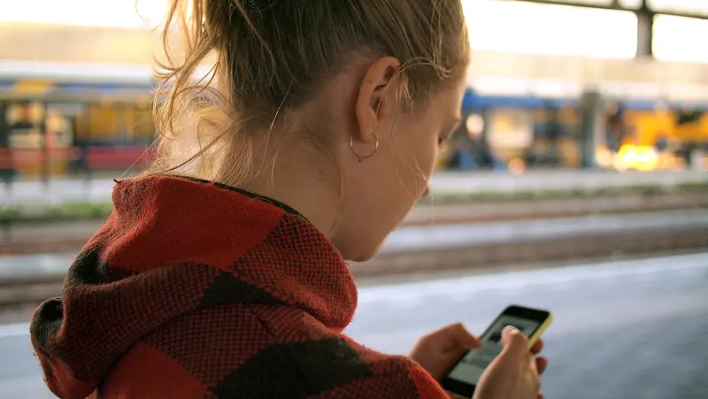 Traveler checking a smartphone at a train station