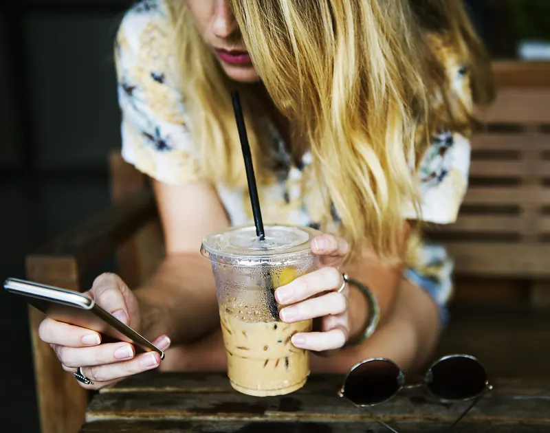Person texting on a smartphone at a cafe